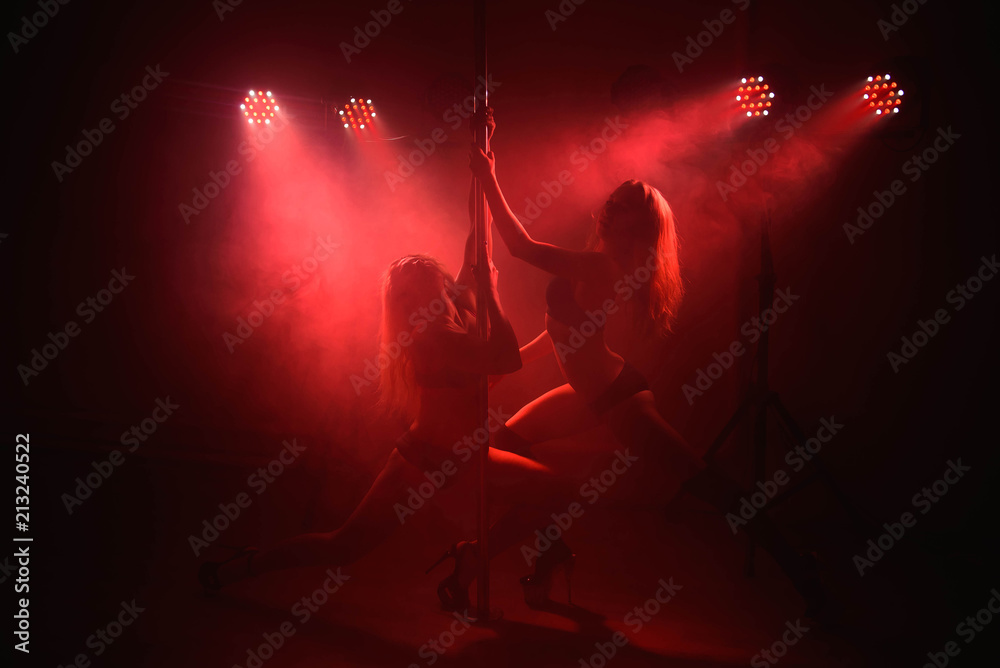 Two young girls doing acrobatic tricks with a pole - obrazy, fototapety, plakaty 