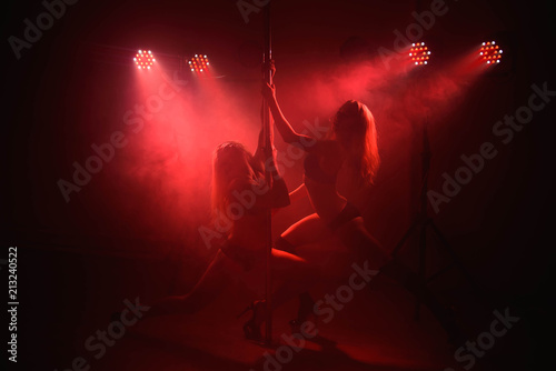 Two young girls doing acrobatic tricks with a pole
