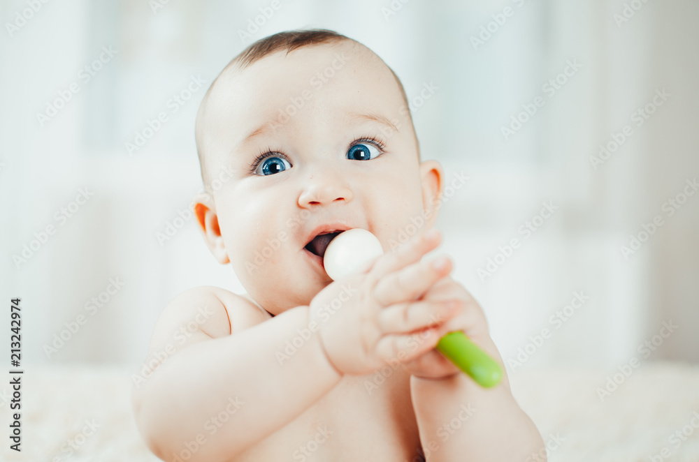 baby chest sitting with a rubber spoon in her hands playing with it baby chest sitting with a rubber spoon in her hands playing with it