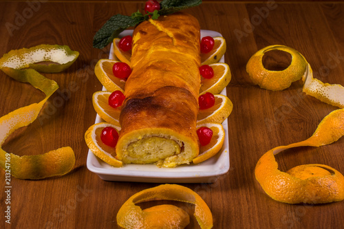 Rocambole de laranja no prato branco no fundo de madeira
