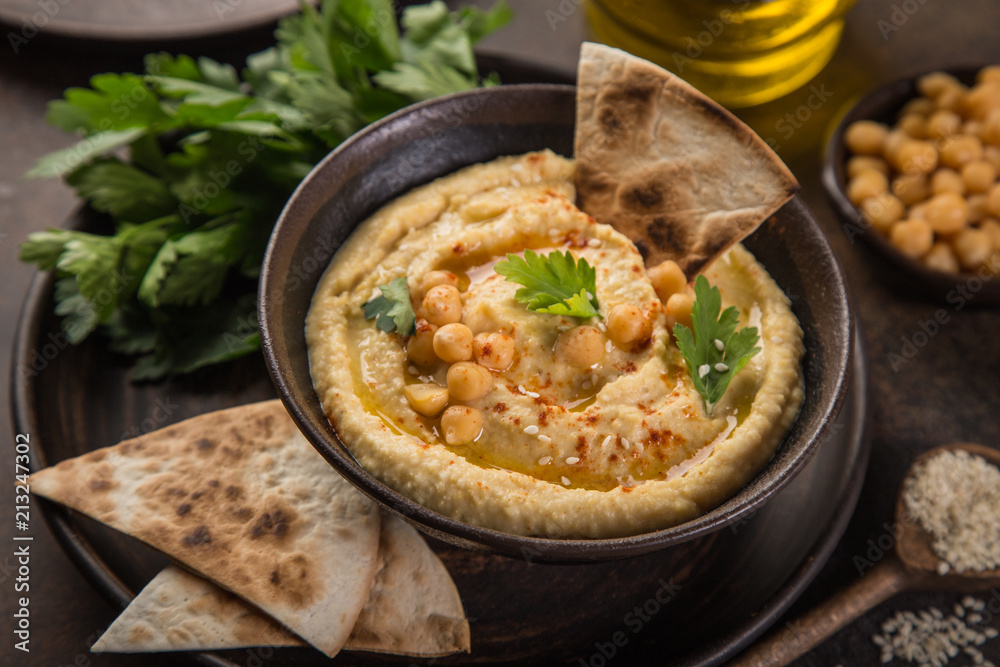 healthy homemade chickpea hummus with olive oil and smoked paprika, wooden background, top view