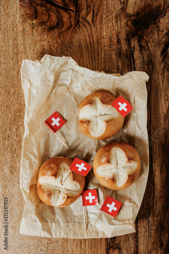 Swiss bread buns called in German 1. Augustweggen baked in Switzerland to celebrate Swiss National Day on August 1st. Swiss flag with white cross on red background. photo