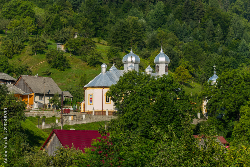a small village with a church in the background of the forest