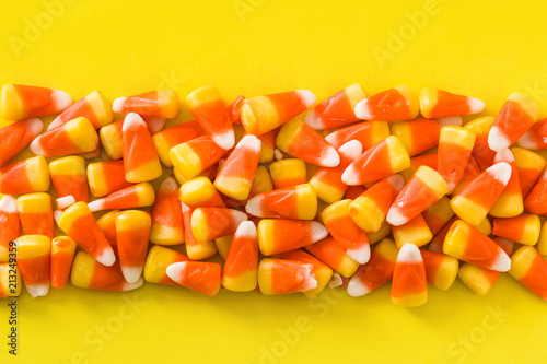Typical halloween candy corn on yellow background.
