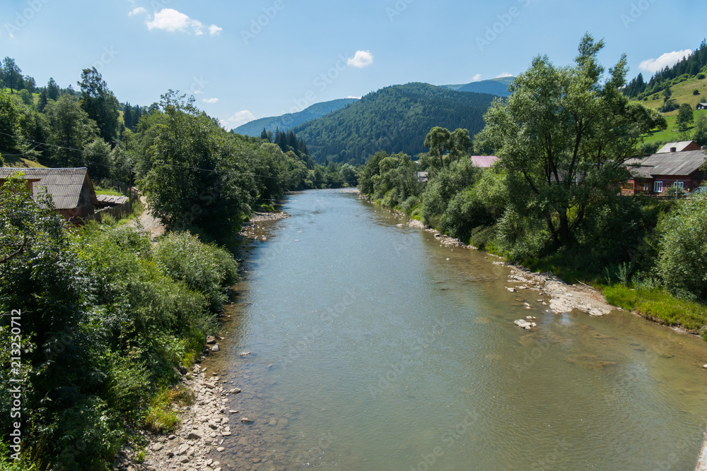 A deep river in a mountainous area surrounded by trees. An ideal place for a fisherman