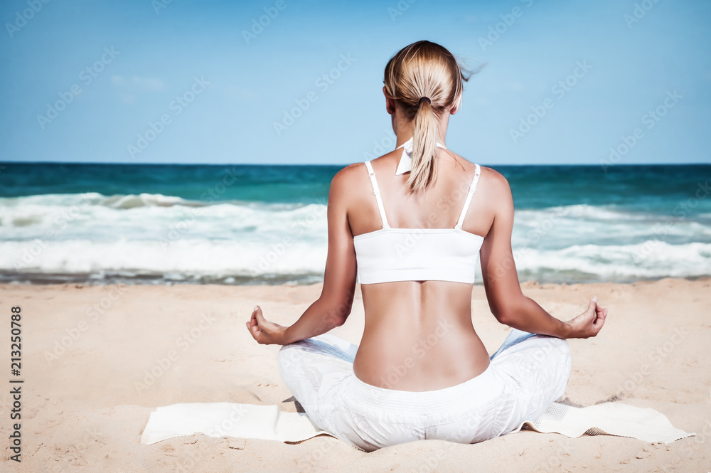 Woman meditating on the beach