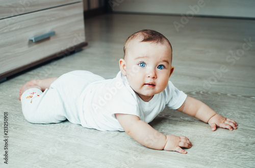 Beautiful baby in the interior. Baby crawling on the floor.