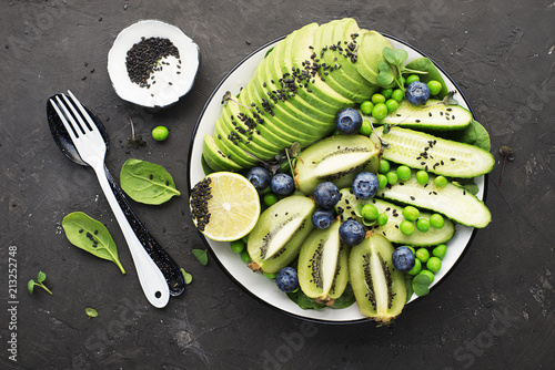 Green fruit vegetables summer detox bowl of salad. Avocado, spinach, cucumber, micro greens, blueberries one plate dish. Top View. photo