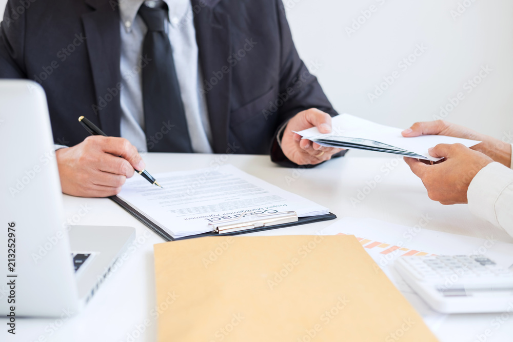 Bribery and corruption concept, bribe in the form of dollar bills, Businessman giving money in the envelope while making deal to agreement a real estate contract and financial corporate