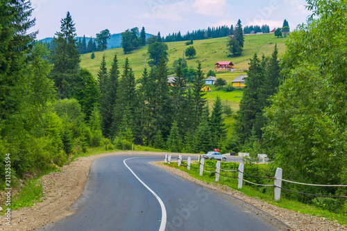 A steep winding road against the backdrop of high green mountain hills