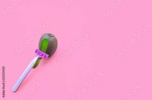 Kiwi fruit and razor on violet background. Hair removal concept.