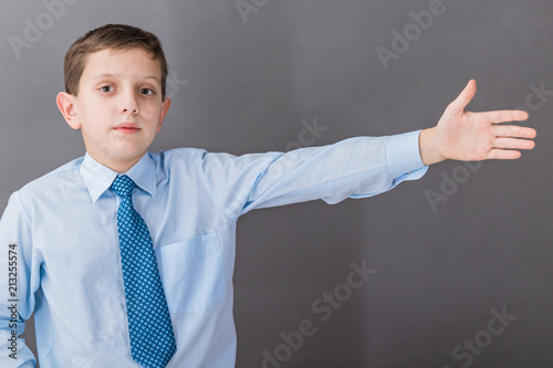The boy standing near the blackboard, emotionally demonstrates something and strongly gestures, pointing aside