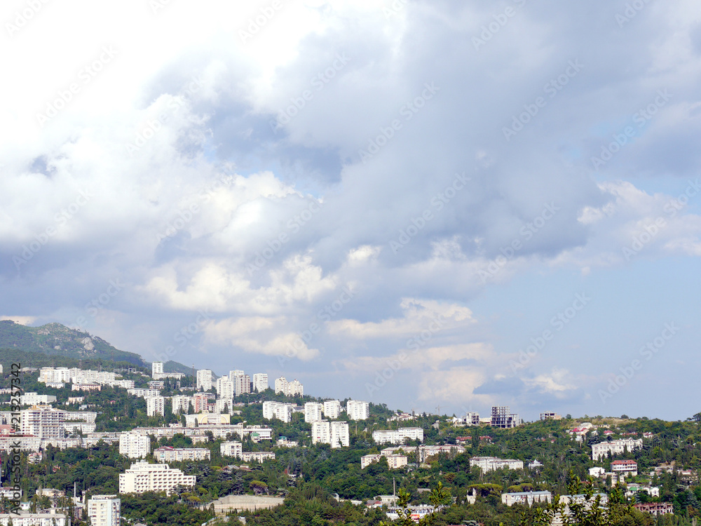 A large resort town with high white sanatoriums and houses on the background of a green forest mountain slope