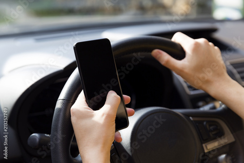 Woman using smartphone while driving the car - transportation and vehicle concept