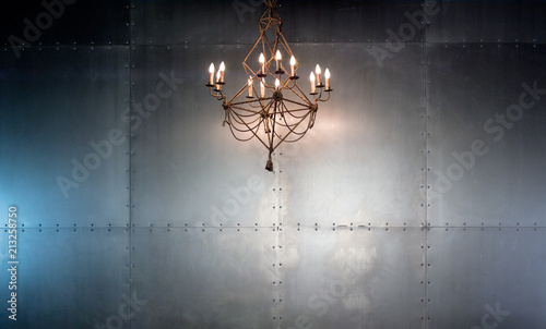 Illuminated chandelier against industrial metal wall