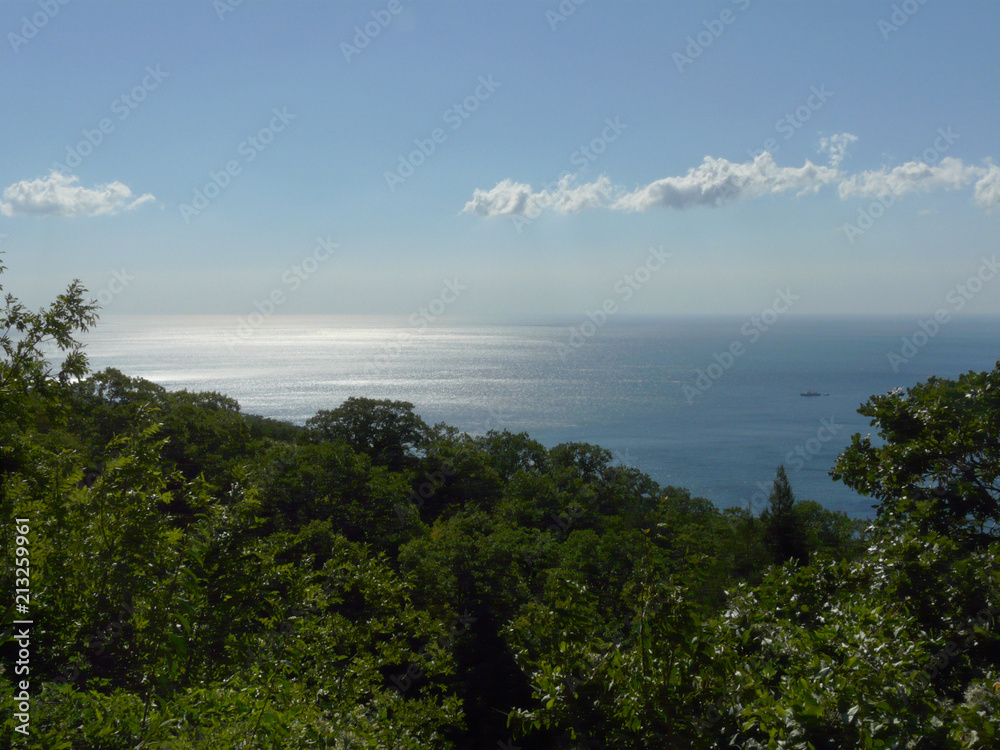 Obraz premium A magnificent landscape stretching away to the horizon line of the sea with a blue sky on it and rare clouds and an iodine boat sailing along the shore.
