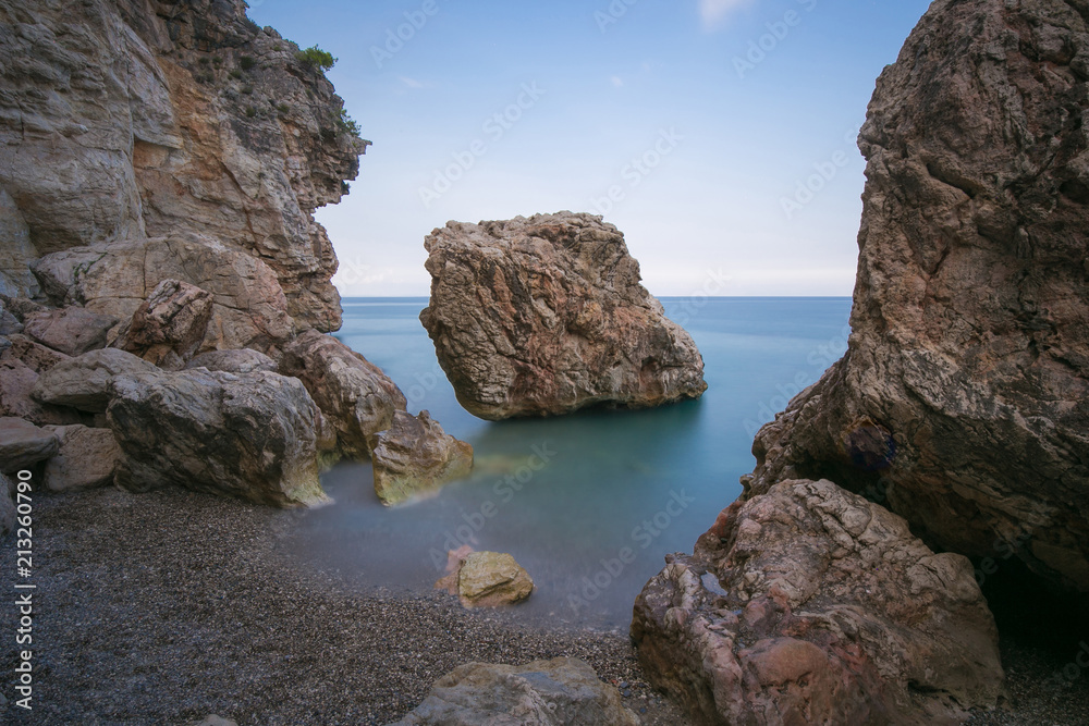 Beautiful seascape with pebble beach and rocks in the water. Coastal landscape on long exposure.