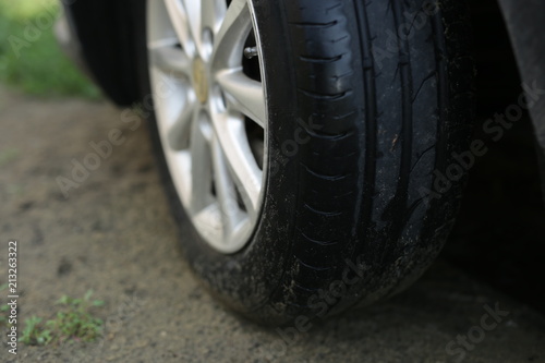 black wheel of a gray car on the sandy ground © Sergey