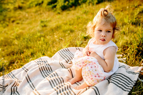 little girl sitting on a blanket in the Park at sunset
