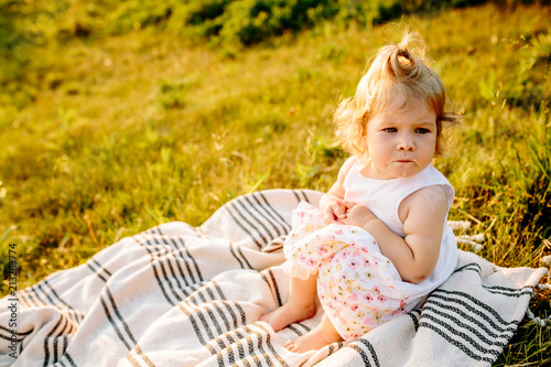little girl sitting on a blanket in the Park at sunset