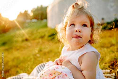 little girl sitting on a blanket in the Park at sunset