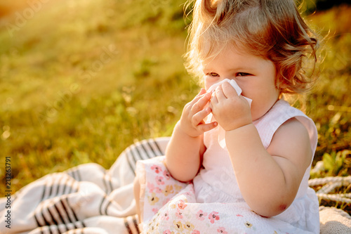 little girl sitting on a blanket and using napkin in the Park at sunset