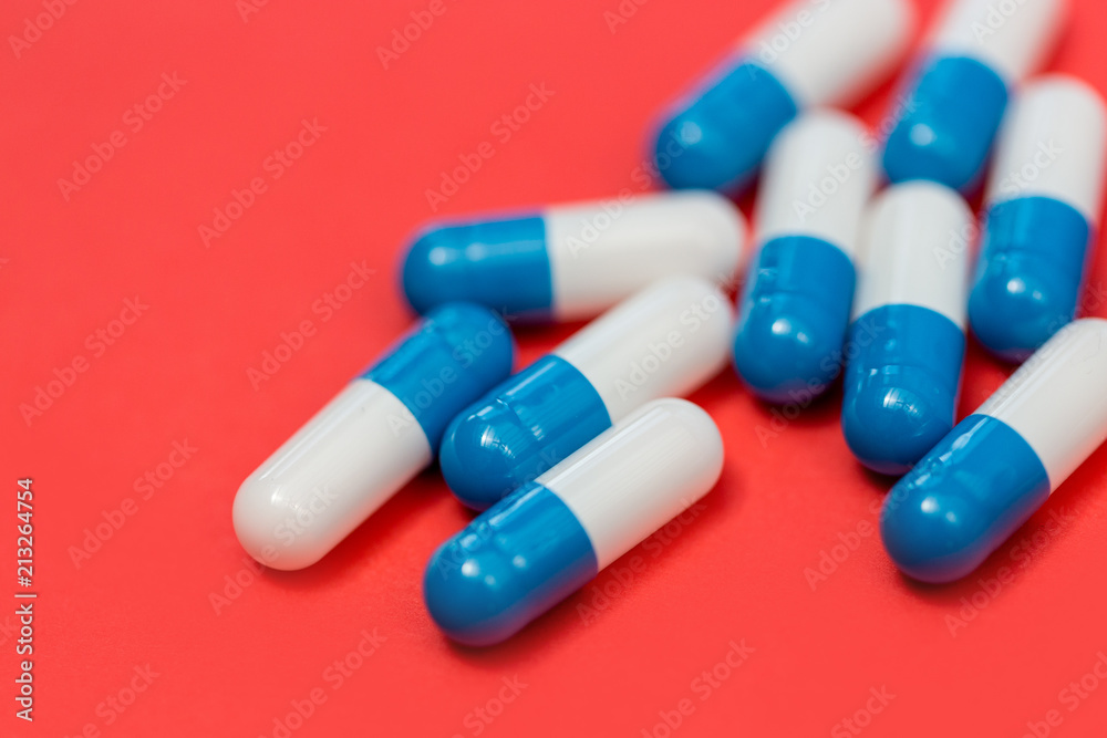 Drugs pills capsules heap on red background