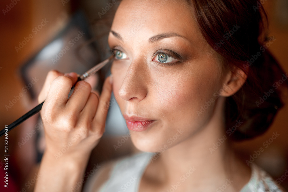 Process of making makeup. Make-up artist working with brush on model face. Portrait of young brunette woman in beauty saloon interior Process of making makeup. Make-up artist working with brush on model face. Portrait of young brunette woman in beauty saloon interior