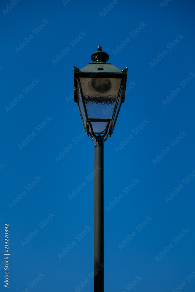 vintage dark green street lamp with a blue sky background