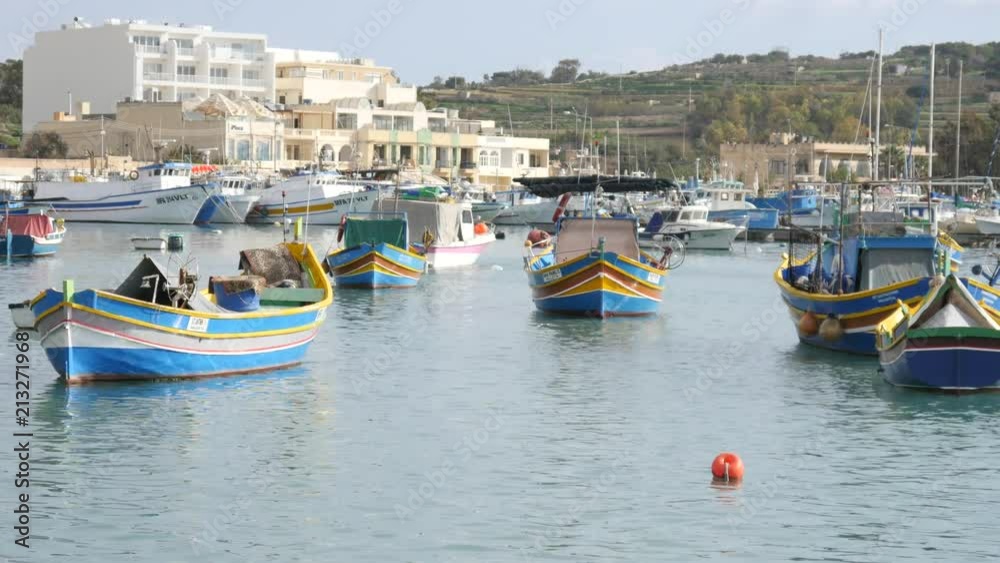 Marsaxlokk, Malta - beautiful fishing village architecture with colored boatsat at anchor in a bay Marsaxlokk, Malta - beautiful fishing village architecture with colored boatsat at anchor in a bay