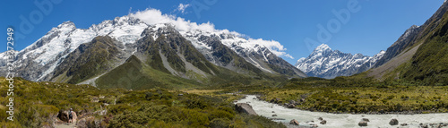Panoramic view of a hiker walking towards Mount Cook beside a river in Aoraki Mount Cook national park  south island  New Zealand