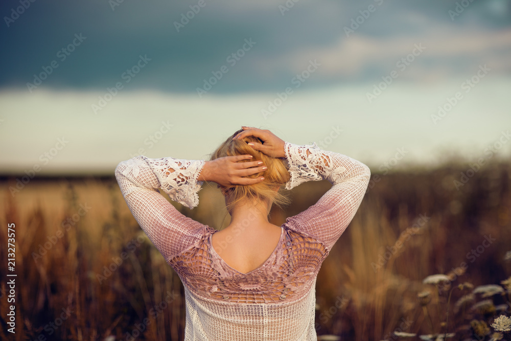 Beautiful blonde woman with long hair standing in a rural flower field ...