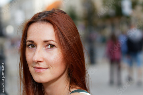 Young beautiful redhead woman looking flirty walking down a street