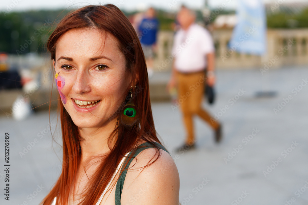 So happy pretty young beautiful woman standing on the street and laughing with butterfly painting on her cheek