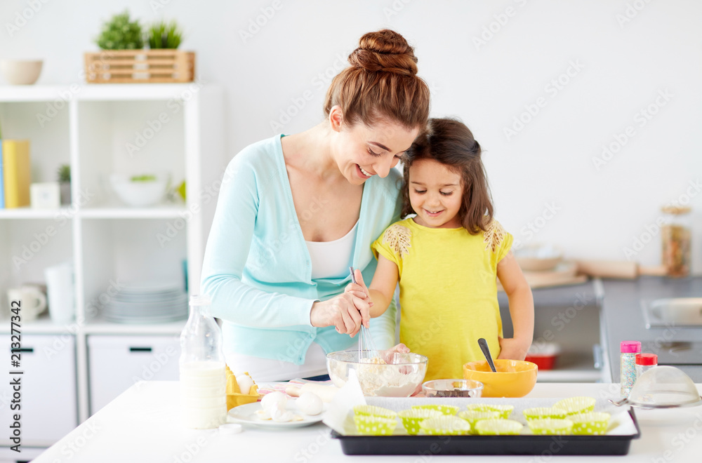 family, cooking, baking and people concept - happy mother and little daughter making batter for muffins at home kitchen family, cooking, baking and people concept - happy mother and little daughter making batter for muffins at home kitchen