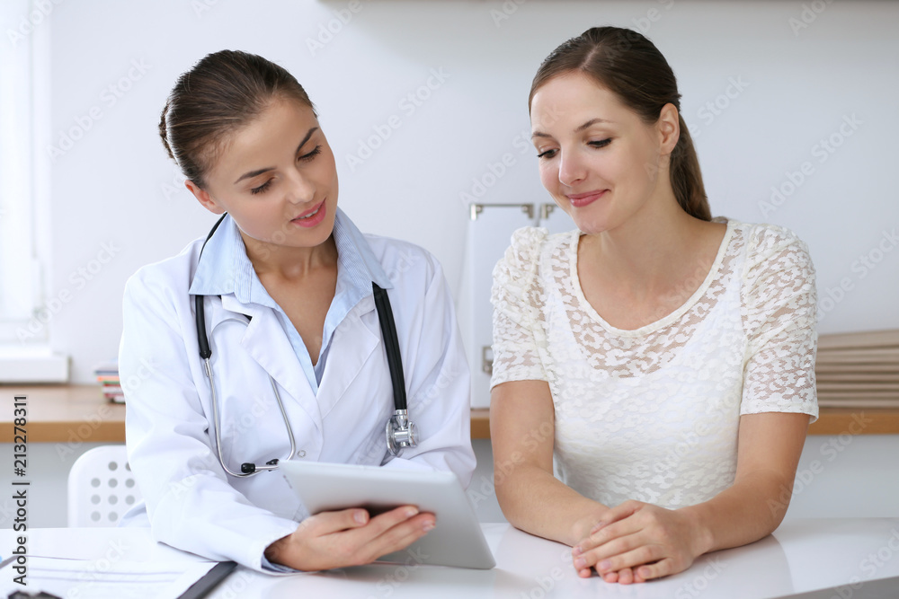 Doctor and patient having a pleasure talk while sitting at the desk at hospital office. Healthcare and medicine concept Doctor and patient having a pleasure talk while sitting at the desk at hospital office. Healthcare and medicine concept