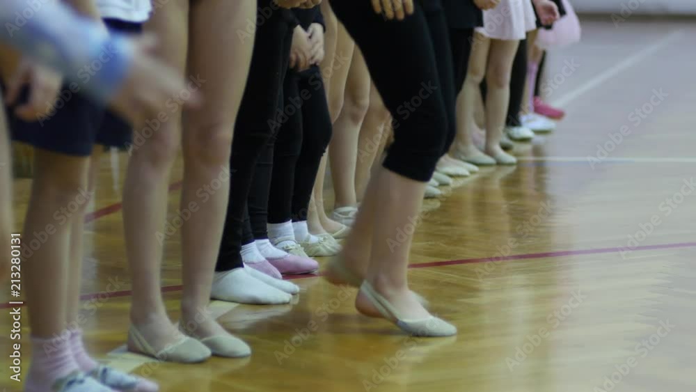 Children gym class for girls - a group engaged in dance gymnastics - legs row Children gym class for girls - a group engaged in dance gymnastics - legs row