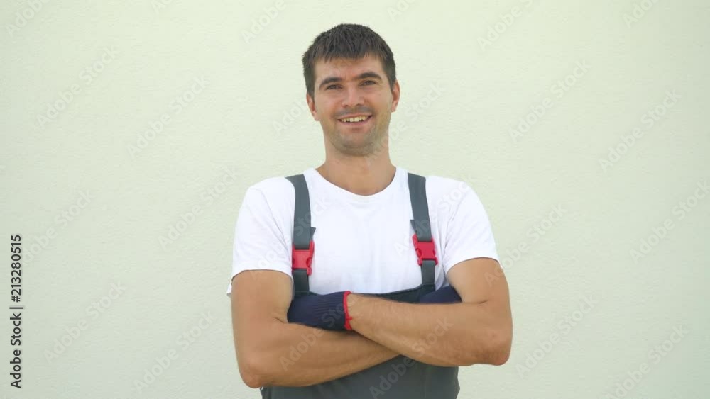 Portrait happy caucasian male industrial worker in work clothes crossing hands looking at camera isolated on light background with free space and copy space. Construction, architect, emotion concept Portrait happy caucasian male industrial worker in work clothes crossing hands looking at camera isolated on light background with free space and copy space. Construction, architect, emotion concept