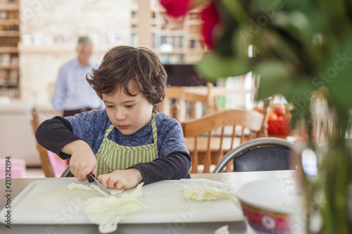 Boy cutting cabbage on chopping board at home