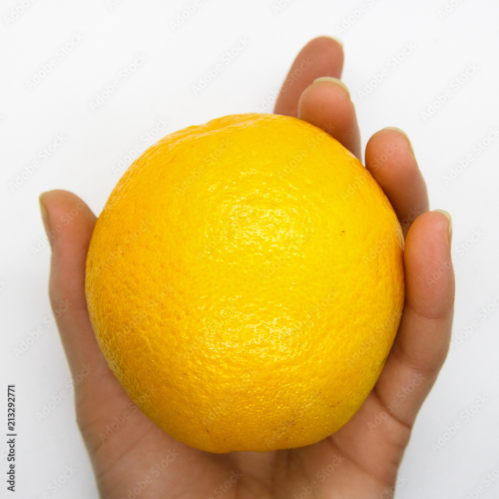 The woman's hand is holding an orange The woman's hand is holding an orange