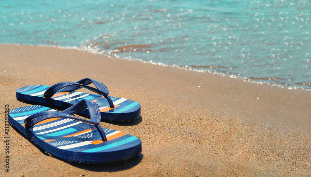 Naklejka premium blue slippers on the beach on the sand