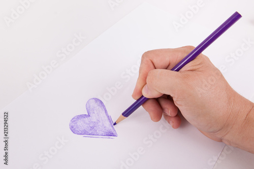 Hand sketching a purple heart with a coloring mapping pencil on white background  photo