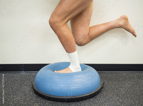 Athlete with a sprained ankle doing strengthening and balance exercises on a bosu ball