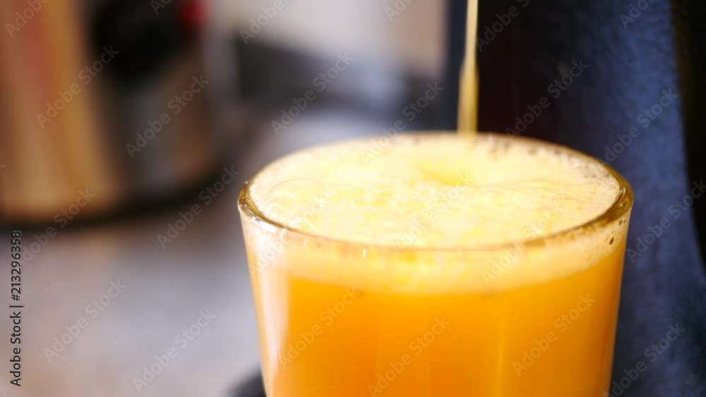 Cooking fresh juice from oranges pouring it in glass cup Cooking fresh juice from oranges pouring it in glass cup