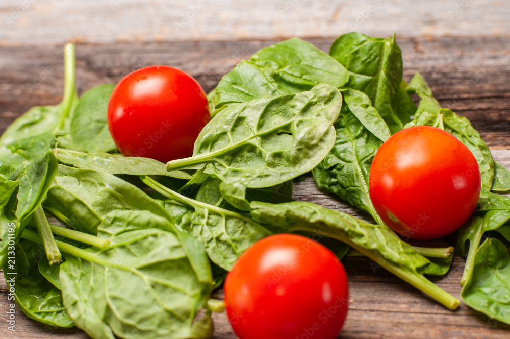 Fresh tomatoes and spinach on wooden table