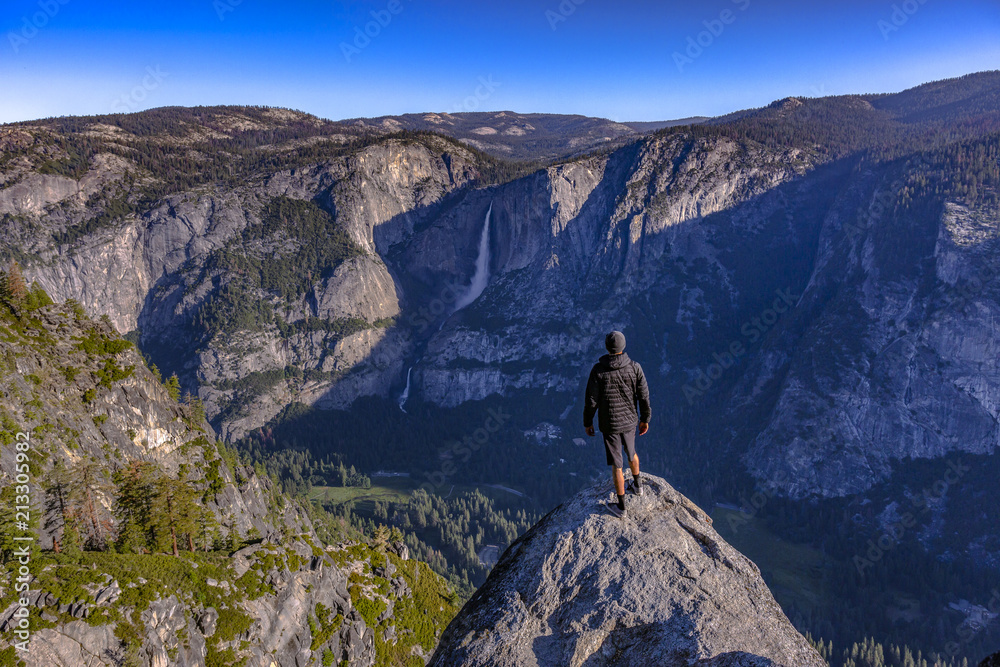 Man stand on cliff in Yosemite Valley near sunrise