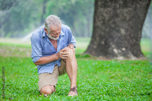 Картината върху платно Senior man sitting or flop falling  in autumn park and having knee pain