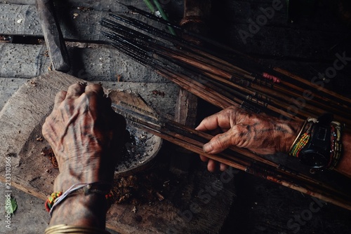Muara Siberut, Mentawai Islands / Indonesia - Aug 15 2017: Tribal elder Toikot poisoning arrowheads for hunting at his jungle home photo