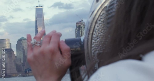 Close up of hand with engagement ring with New York City skyline in background.