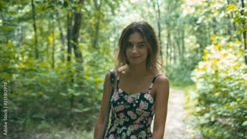 Cheerful young woman in forest walking on road, slow motion, shallow depth of field Cheerful young woman in forest walking on road, slow motion, shallow depth of field